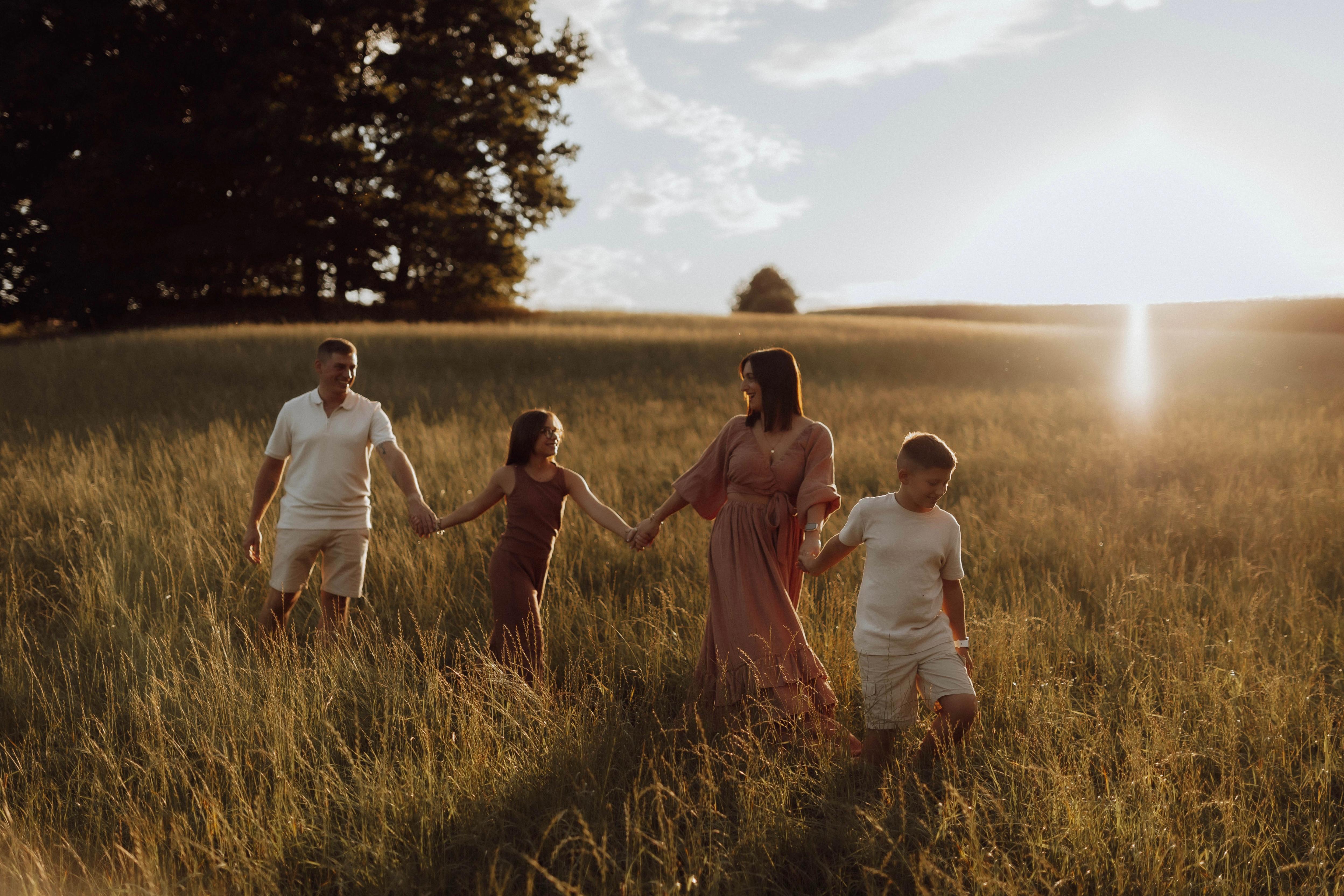 Junge Familie spaziert gemeinsam lachend über eine sommerliche Blumenwiese -- Familienfotografie von Simple Moments