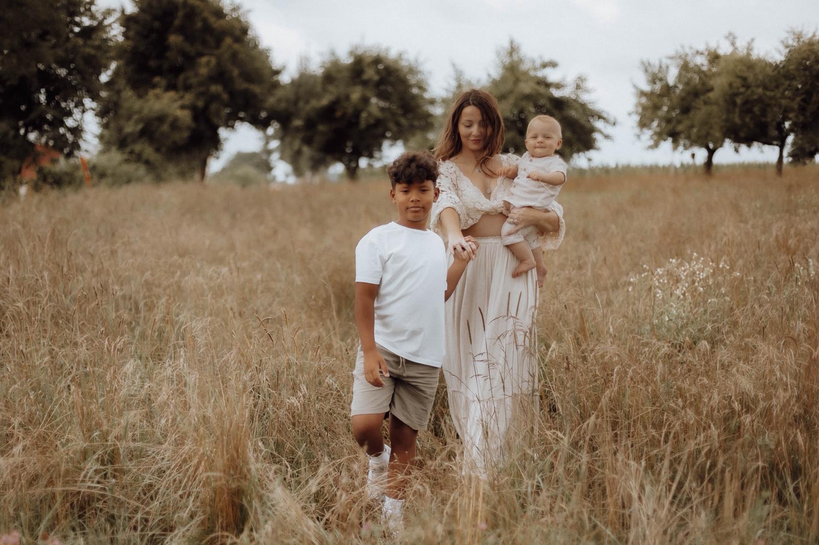 Mutter mit zwei Kindern auf einer sommerlichen Wiese