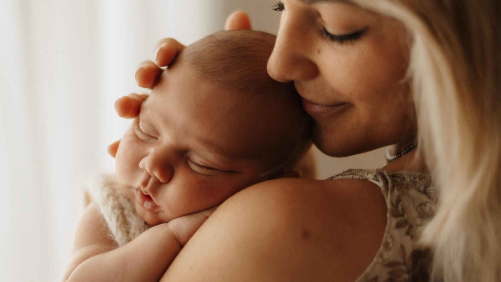 Mama hält ihr schlafendes Neugeborenes eng an sich und schließt die Augen -- Newborn-Shooting von Simple Moments